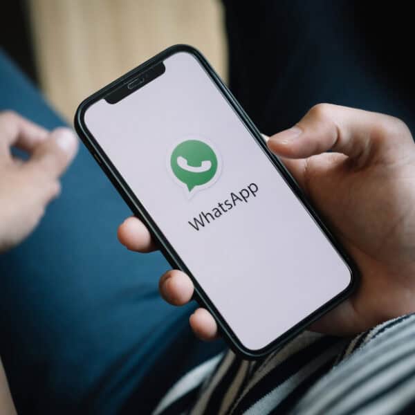 Monipuolinen WP-asiakastuki WhatsAppissa - Avosorsa Oy Henkilö pitelee älypuhelinta, jossa näkyy WhatsApp-logo, symboloiden nopeaa asiakastukea.